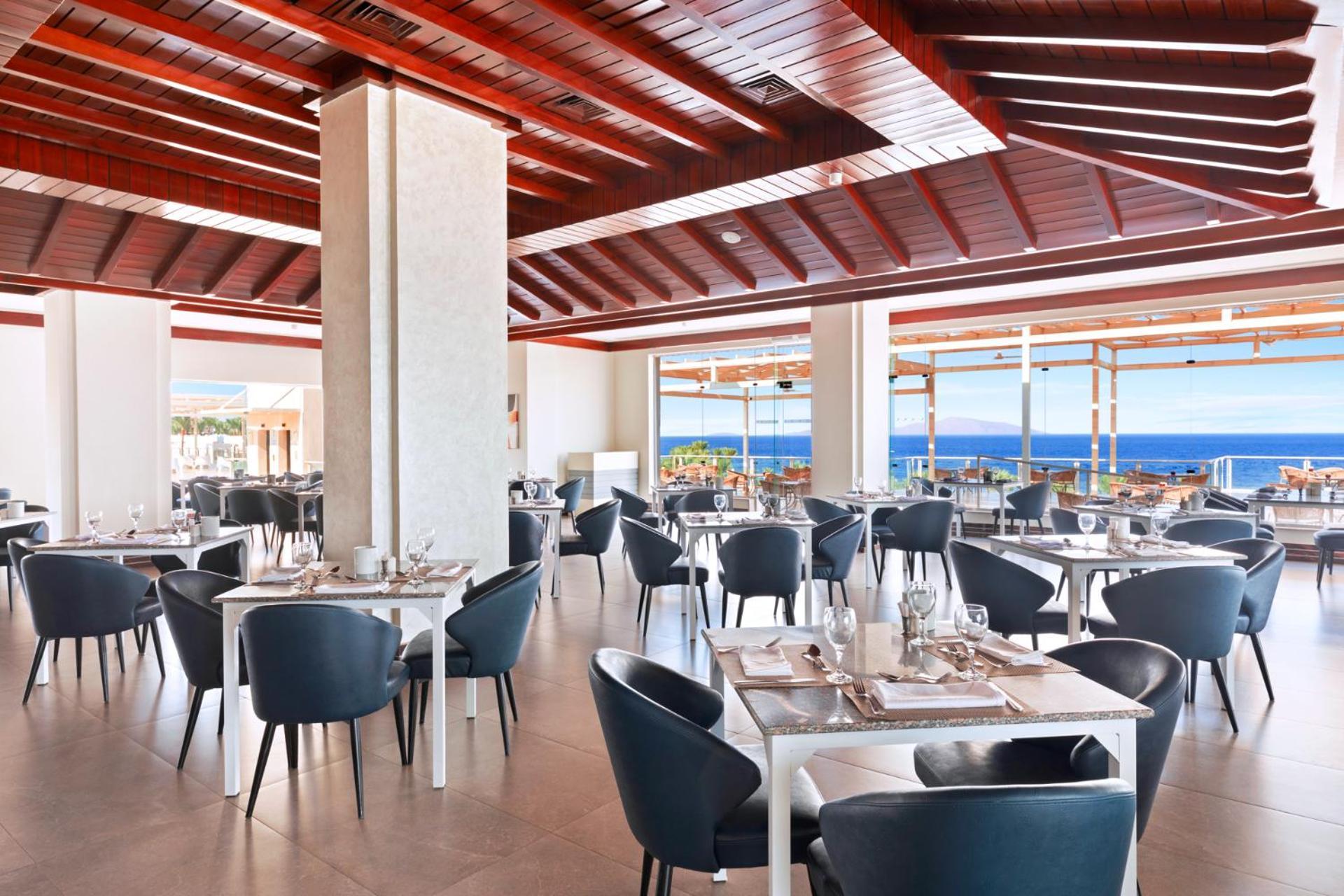 Pickalbatros Royal Grand Sharm - Adults Friendly 16 Years Plus Ngoại thất bức ảnh The photo shows a modern restaurant interior with a spacious and well-lit design. There are several tables set for dining, featuring white tablecloths and elegant dinnerware. The chairs are sleek and dark, contrasting with the bright surroundings. La