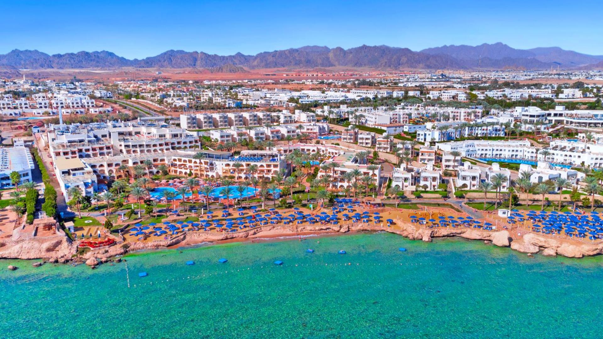 Pickalbatros Royal Grand Sharm - Adults Friendly 16 Years Plus Ngoại thất bức ảnh The photo shows an aerial view of a resort located by the coast. There are several swimming pools surrounded by sun loungers and umbrellas, as well as a beach area with clear turquoise water. In the background, there are multiple buildings of the res