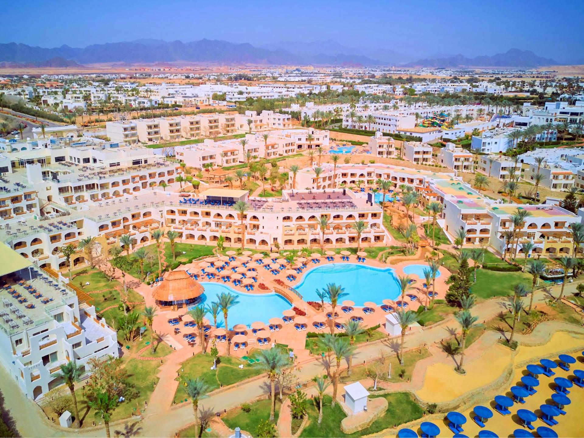 Pickalbatros Royal Grand Sharm - Adults Friendly 16 Years Plus Ngoại thất bức ảnh The photo shows an aerial view of a resort complex. There are several buildings arranged around a central area that features swimming pools. The pools are surrounded by palm trees and lounge chairs, indicating a tropical or sunny climate. In the back
