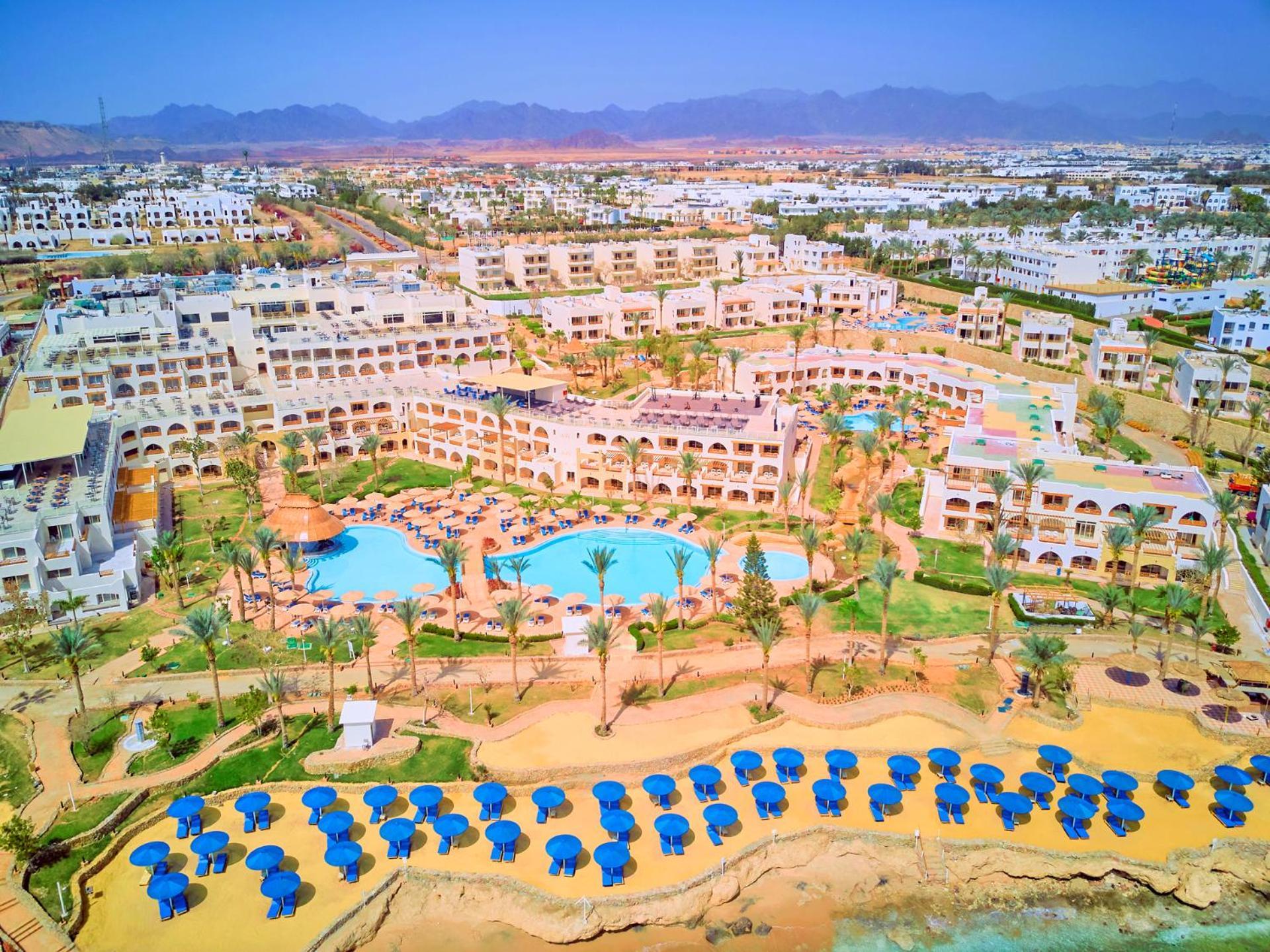 Pickalbatros Royal Grand Sharm - Adults Friendly 16 Years Plus Ngoại thất bức ảnh The photo shows a large resort complex set in a scenic location, likely near a beach. The layout features multiple buildings with a Mediterranean style of architecture, surrounded by lush greenery and palm trees. Central to the resort is a swimming p