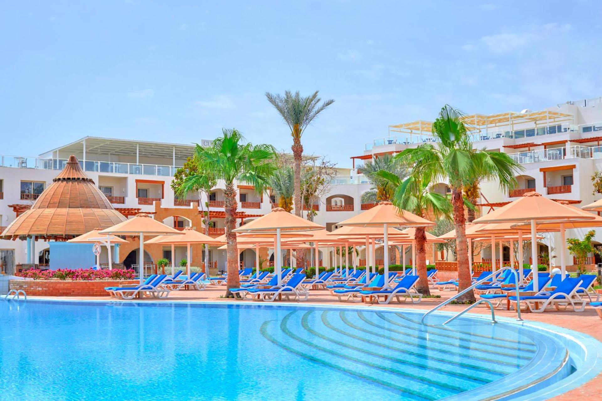 Pickalbatros Royal Grand Sharm - Adults Friendly 16 Years Plus Ngoại thất bức ảnh The photo depicts a resort scene featuring a beautiful swimming pool with clear blue water. Surrounding the pool are several lounge chairs arranged under large umbrellas, providing shade. In the background, there are palm trees that enhance the tropi