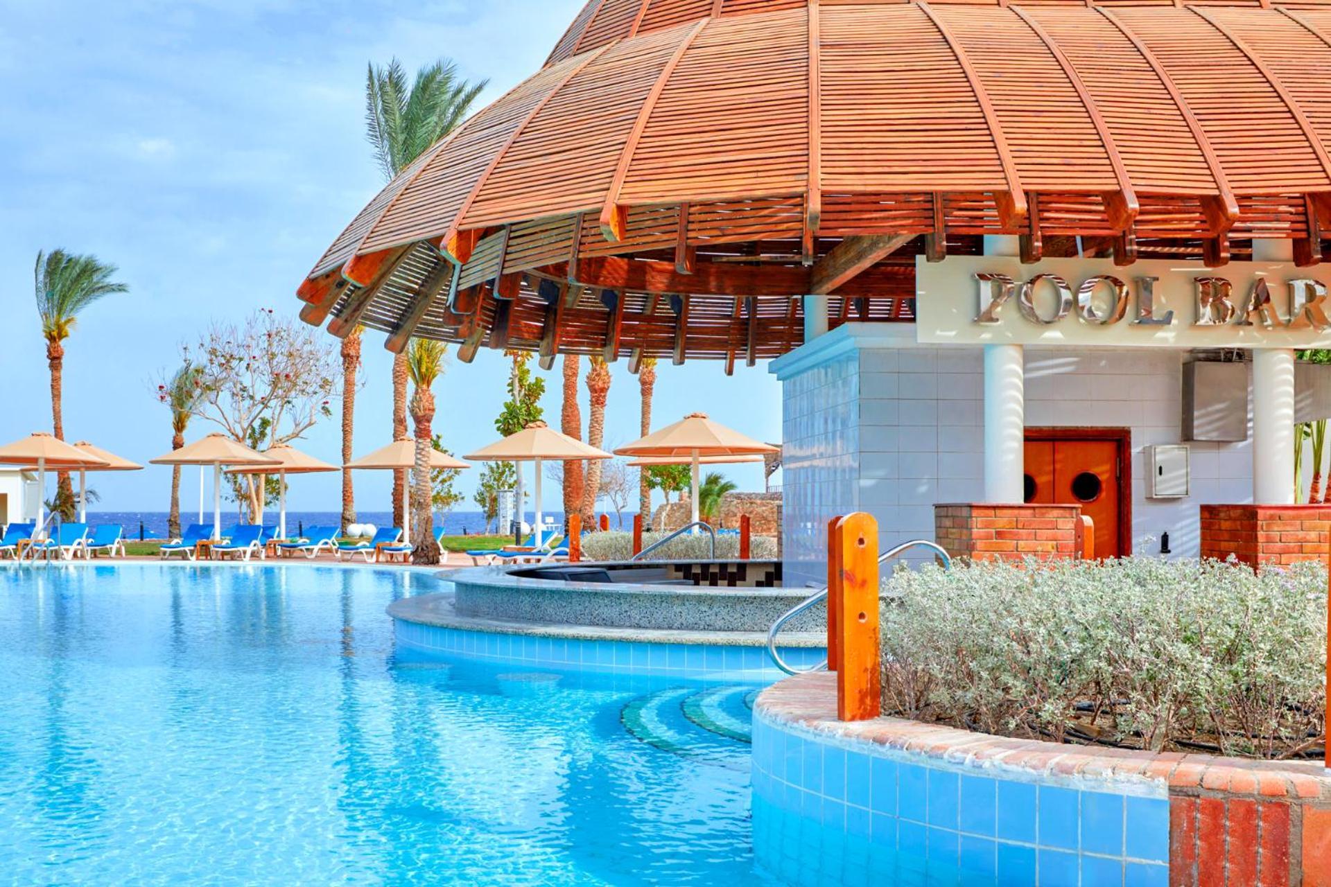 Pickalbatros Royal Grand Sharm - Adults Friendly 16 Years Plus Ngoại thất bức ảnh The photo depicts a picturesque pool area at a resort. In the foreground, there is a clear and inviting swimming pool with curved edges, surrounded by a light blue tile border. To the side, a pool bar is visible with a wooden roof and stylish archite